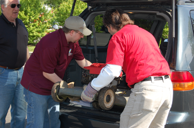 men lifting lawn mower